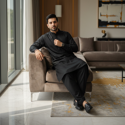 Man wearing PASHA black soft cotton shalwar kameez relaxing in luxury home interior