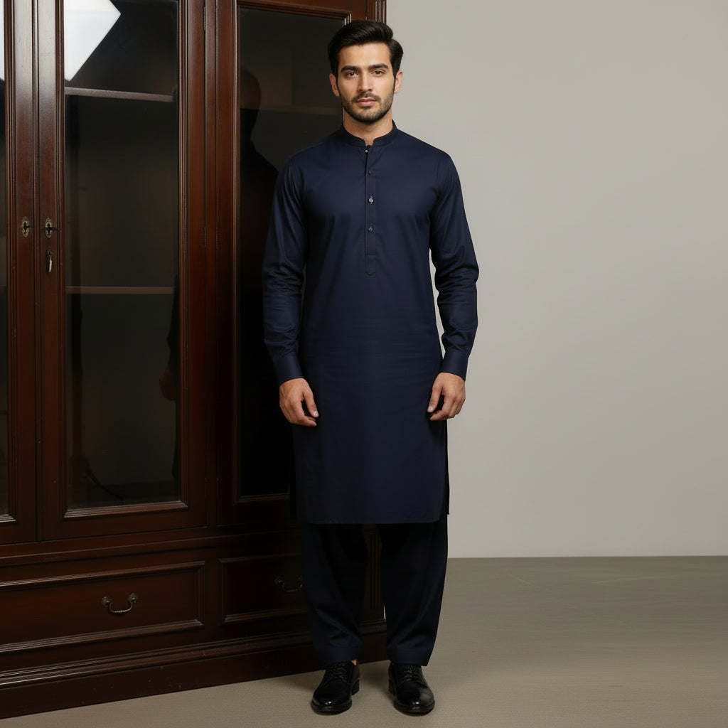 Man wearing a navy pasha cotton kurta standing in front of a wooden wardrobe.