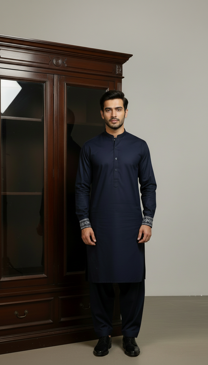 Man wearing a navy blue pasha cotton kurta standing in front of a wooden wardrobe.