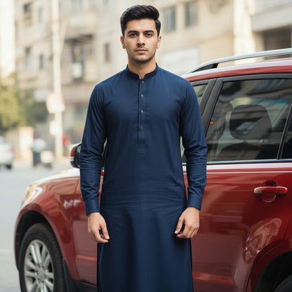 Man in a navy pasha cotton traditional outfit standing next to a red car in an urban setting
