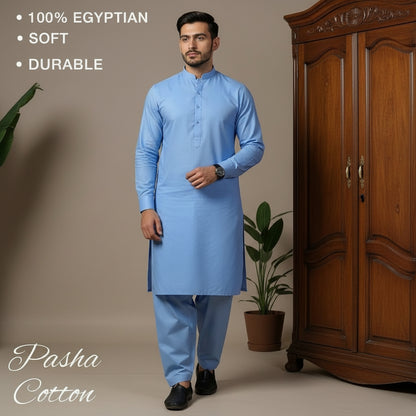 Man wearing a sky blue kurta standing next to a wooden wardrobe with 'Pasha Cotton' branding.